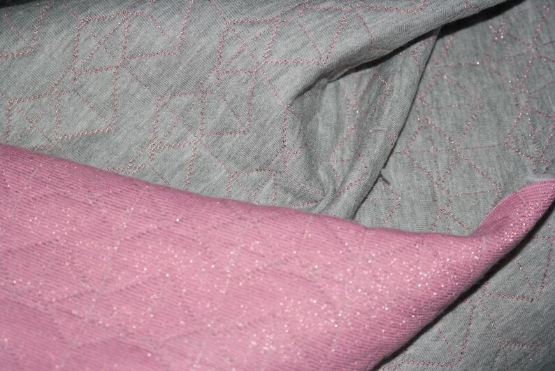 May include: Two pieces of fabric, one gray and one pink, with a diamond pattern. The fabric is soft and textured.