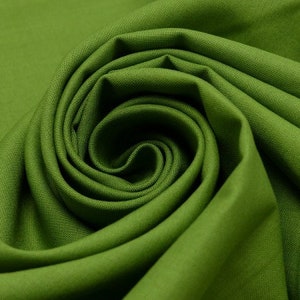 Könnte beinhalten: Nahaufnahme eines grünen Stoffes, der zu einer Spirale gefaltet und gedreht ist. Der Stoff hat eine glatte, gleichmäßige Textur.