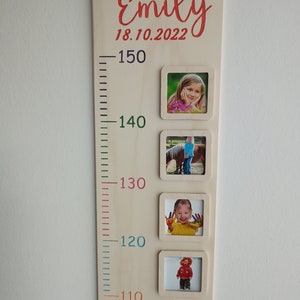 May include: A wooden growth chart with a white background and colourful numbers. The chart has a name, "Emily", and a date, "18.10.2022", written in red. There are five photo frames with pictures of a child at different ages.