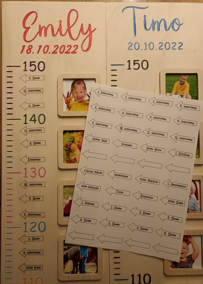 May include: A wooden growth chart with two sections, one for Emily and one for Timo. Each section has a ruler with measurements in centimetres, a photo frame, and a series of stickers with milestones and ages. The stickers are arranged in a row, with arrows pointing to the right. The stickers include milestones such as "First Birthday", "First Steps", "First Tooth", "Kindergarten", and "First Grade".