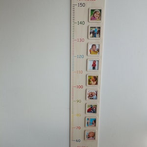 Pode incluir: Um gr&aacute;fico de crescimento de madeira com uma r&eacute;gua e molduras para fotos. O gr&aacute;fico &eacute; decorado com linhas e n&uacute;meros coloridos. A parte superior do gr&aacute;fico tem o nome "Emily" e a data "18.10.2022". O gr&aacute;fico tamb&eacute;m inclui o texto "23:59Uhr 49cm 3190g".