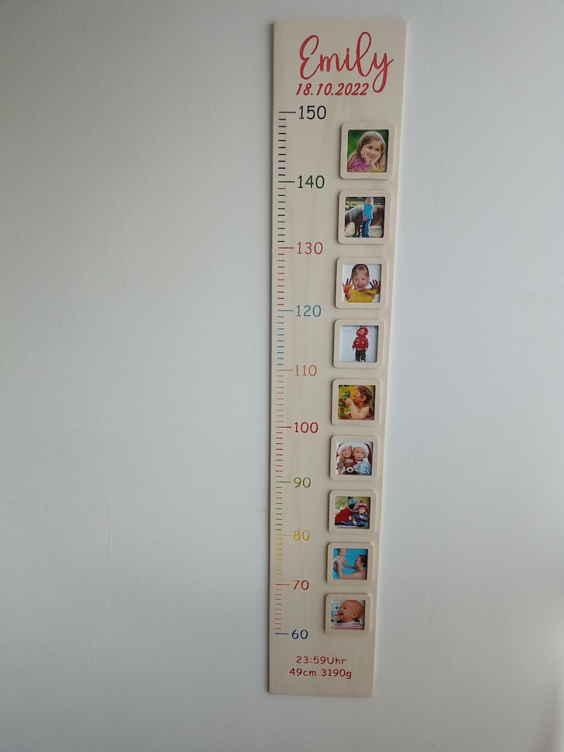 Pode incluir: Um gr&aacute;fico de crescimento de madeira com uma r&eacute;gua e molduras para fotos. O gr&aacute;fico &eacute; decorado com linhas e n&uacute;meros coloridos. A parte superior do gr&aacute;fico tem o nome "Emily" e a data "18.10.2022". O gr&aacute;fico tamb&eacute;m inclui o texto "23:59Uhr 49cm 3190g".