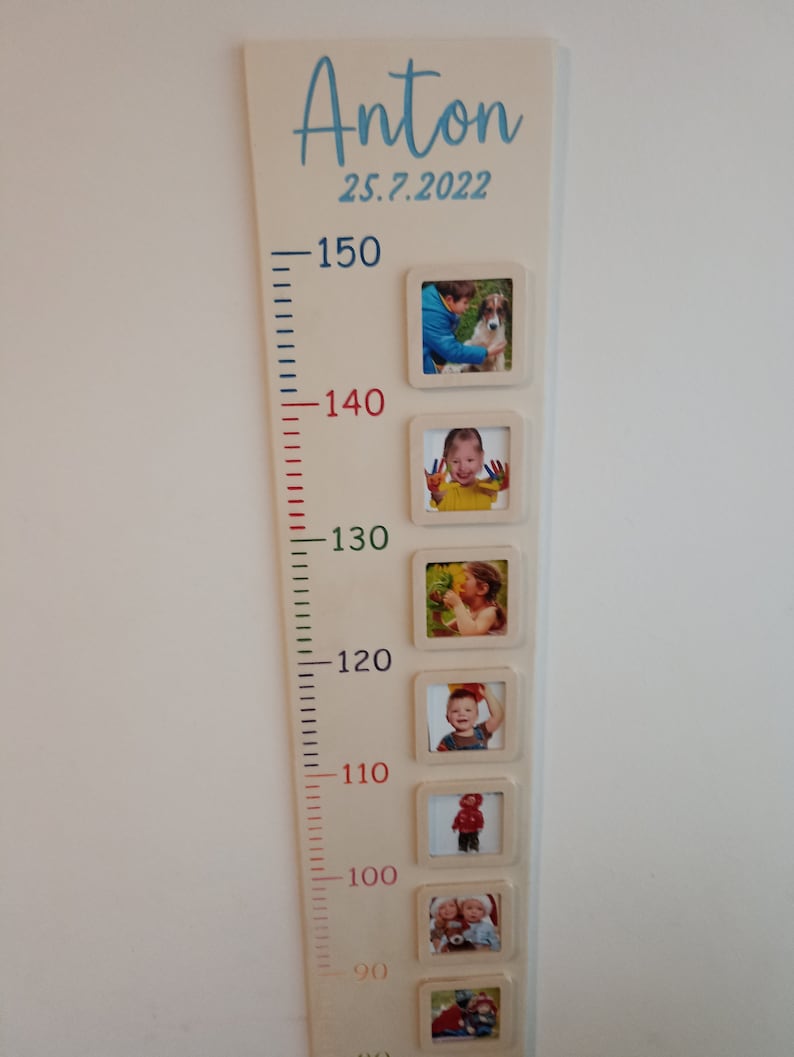 Pode incluir: Um gr&aacute;fico de crescimento de madeira com fundo branco e uma inscri&ccedil;&atilde;o azul que diz "Anton 25.7.2022". O gr&aacute;fico tem uma r&eacute;gua com marcas em cent&iacute;metros de 90 a 150. H&aacute; seis molduras de fotos com imagens de uma crian&ccedil;a em diferentes idades.