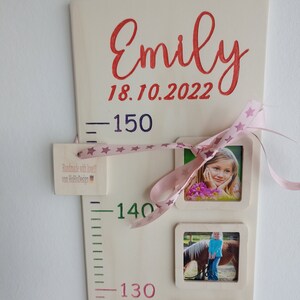 Pode incluir: Um gr&aacute;fico de crescimento de madeira com uma fita rosa e estrelas, incluindo um nome, uma data e tr&ecirc;s molduras para fotos. O gr&aacute;fico tem um fundo branco com marcas verdes e rosas. O texto no gr&aacute;fico diz "Emily 18.10.2022".