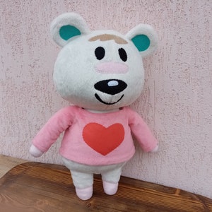 May include: White plush toy with a pink shirt and a red heart on the front. The toy has a brown nose and black eyes.