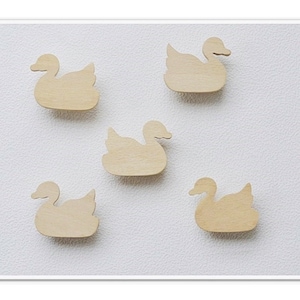 Puede incluir: Cinco formas de cisne de madera sin terminar, cada una con un diseño simple, están dispuestas sobre un fondo blanco.