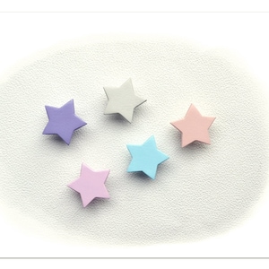 Op de afbeelding: Vijf pastelkleurige papieren sterren op een witte achtergrond. De sterren zijn lichtblauw, roze, paars, lichtgrijs en donkerroze.
