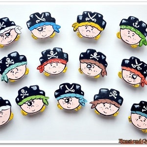 May include: Twelve wooden pirate head ornaments with black hats, eyepatches, and colorful bandanas. Each ornament has a different facial expression and bandana color.
