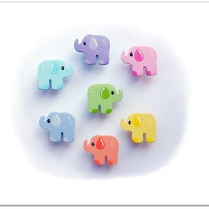 Könnte beinhalten: Sieben hölzerne Elefantenfiguren in verschiedenen Pastellfarben, darunter hellblau, rosa, gelb, grün und lila. Die Elefanten sind alle nach vorne gerichtet, mit erhobenem Rüssel.