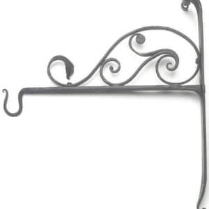 May include: A black metal wall-mounted sign holder with a decorative scroll design. The holder has a hook on the left side and a vertical support on the right side.