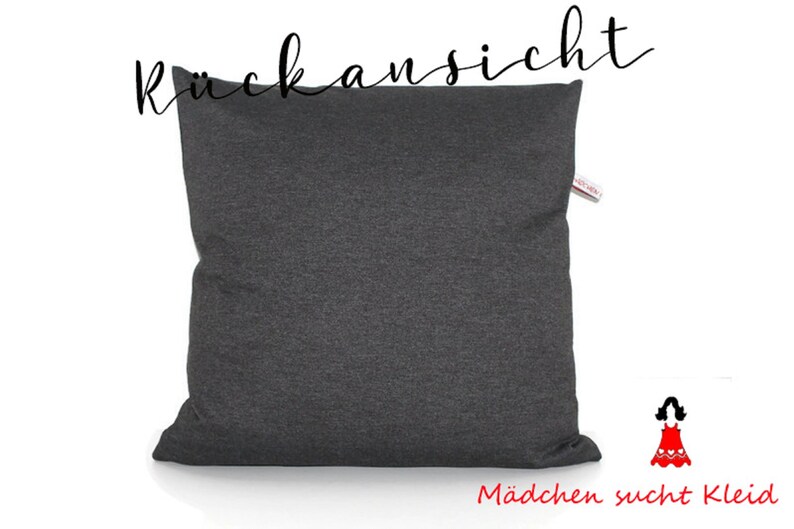 May include: A dark gray pillow with the German word "R&uuml;ckansicht" written in black above it. The text "M&auml;dchen sucht Kleid" is written in red below the pillow.