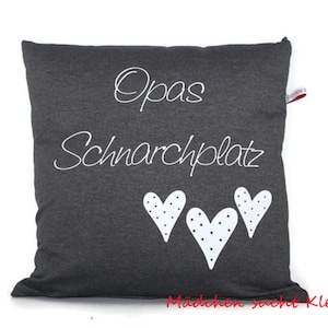 May include: A gray pillow with white text that says "Opa's Schnarchplatz" and three white hearts with black polka dots.