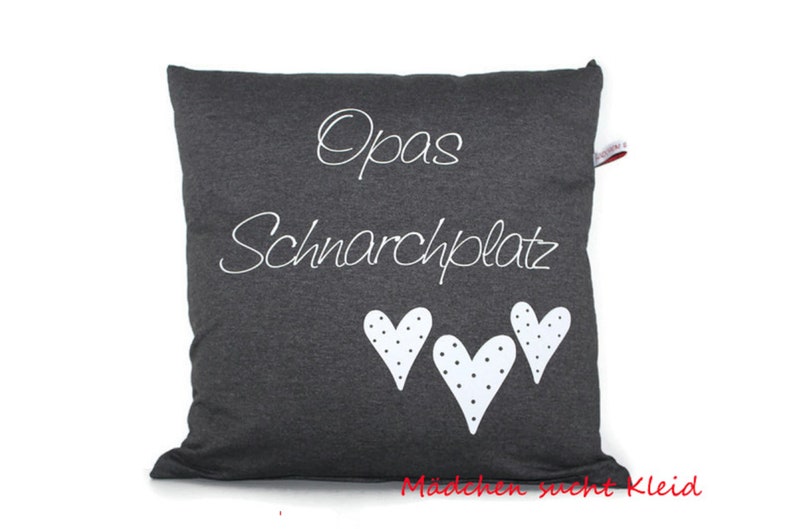 May include: A gray pillow with white text that says "Opa's Schnarchplatz" and three white hearts with black polka dots.
