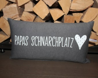 May include: A gray pillow with white text that reads "Papas Schnarchplatz" and a white heart with black dots.
