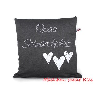 May include: A gray pillow with white text that says "Opa's Schnarchplatz" and three white hearts with black polka dots. The text "Madchen sucht Kleid" is printed in red at the bottom of the pillow.