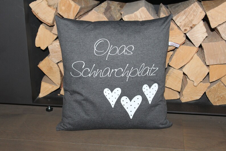 May include: A gray pillow with white text that says "Opa's Schnarchplatz" and three white hearts with black polka dots.