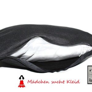 May include: A black pillow with a zipper opening, showing a white inner lining. The pillow has the text "M&auml;dchen sucht Kleid" and "mit Rei&szlig;verschluss" printed on it.
