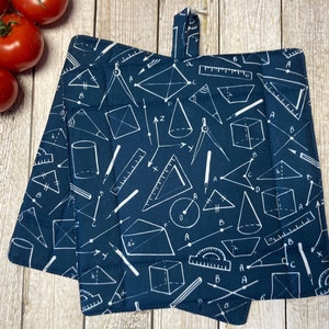 Könnte beinhalten: Zwei blaue Topflappen mit einem weißen geometrischen Muster aus Geodreiecken, Zirkeln, Linealen und Dreiecken.