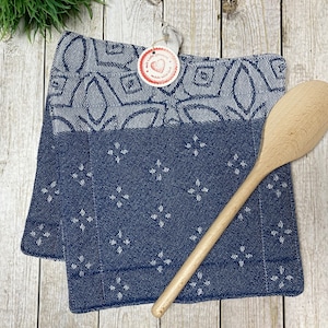 Könnte beinhalten: Zwei blaue und weiße Küchenhandtücher mit einem Holzlöffel darauf. Die Handtücher haben ein weißes Herz mit dem Wort "Love" darauf.