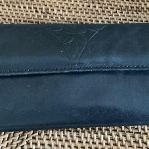 May include: A black leather wallet with a floral design embossed on the front.
