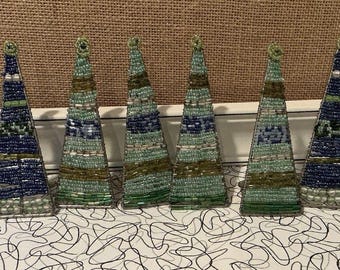 Könnte beinhalten: Eine Sammlung von sieben mit Perlen besetzten Weihnachtsbaumschmuck. Die Ornamente sind dreieckig geformt und weisen eine Vielzahl von Farben auf, darunter grüne, blaue und silberne Perlen. Jeder Baum hat oben eine Schlaufe zum Aufhängen.