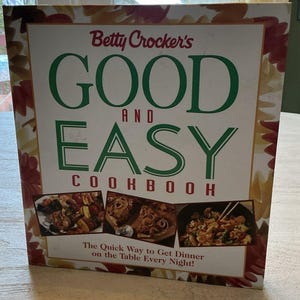 Puede incluir: Una taza de cerámica blanca con un asa negra y el texto "But First, Coffee" en un estilo manuscrito. La taza está sobre una superficie blanca. La taza mide aproximadamente 10 cm de alto.