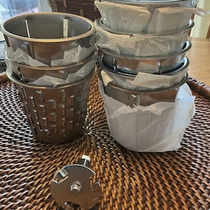 May include: A white ceramic mug with a black handle and the text "But First, Coffee" in a black, handwritten-style font. The mug is on a white surface.