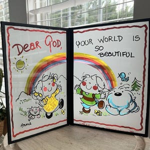 May include: A black framed, two-sided, glass panel with a rainbow and a sun on each side. The left side says "Dear God" and the right side says "Your world is so beautiful". Each side has a cartoon drawing of a person and an animal.