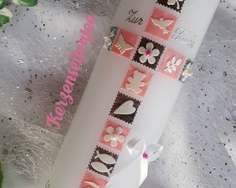 May include: White baptism candle with a pink and brown cross design. The candle has a silver inscription that reads "Clara Josephine 17.0.2019" and "Zur Taufe".