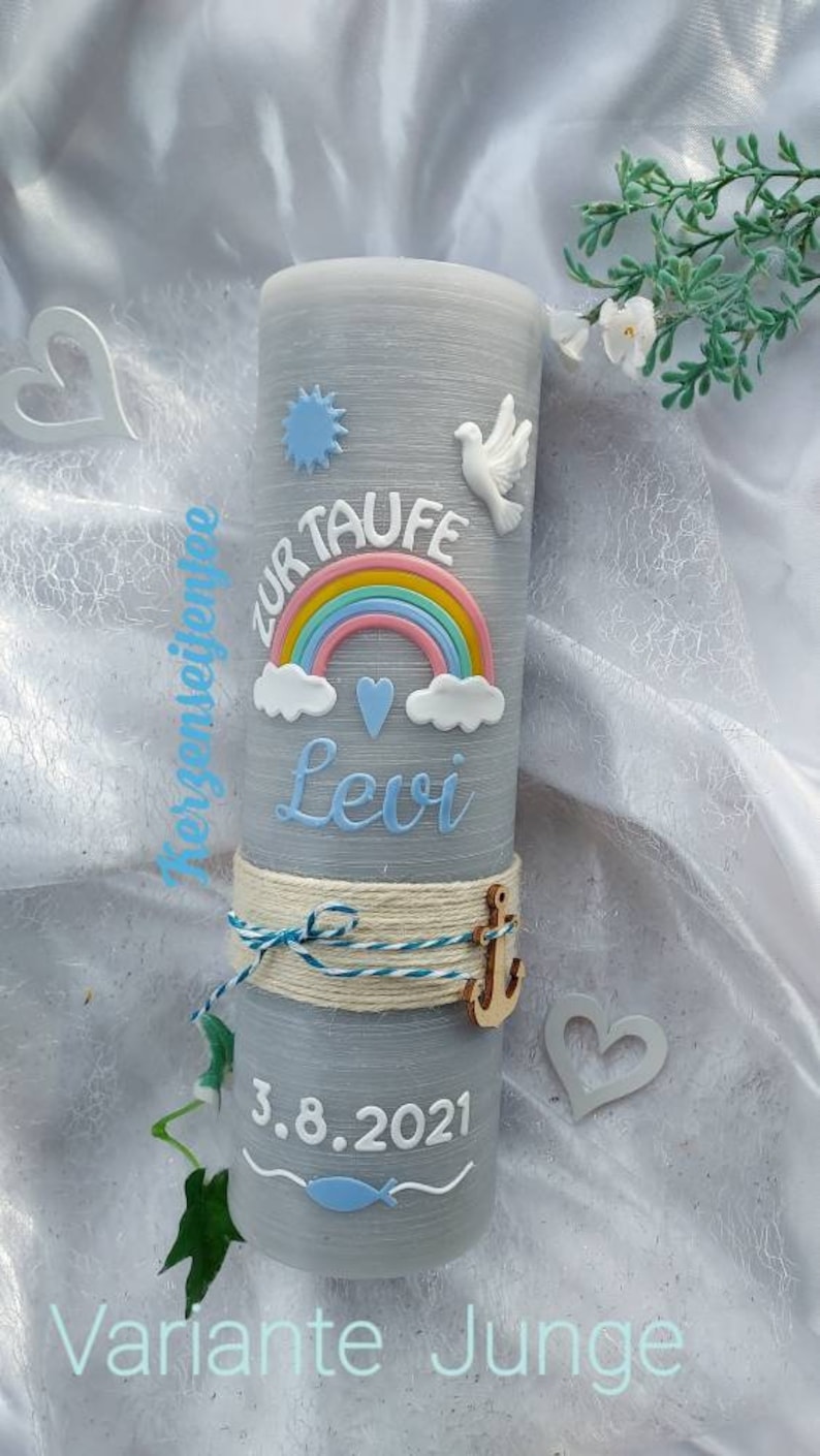 May include: Gray baptism candle with a rainbow, clouds, a dove, and a heart. The candle is decorated with a blue and white rope and a wooden anchor. The text "Zur Taufe Levi 3.8.2021" is written on the candle.  Variante Junge.