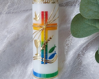 May include: A white cylindrical candle featuring a rainbow-colored cross, a gold dove, a chalice, wheat, and two fish. The text reads Zur Kommunion, LARS PHILIPP, and 19.04.2026. A blue ribbon is tied at the base with a white lace trim.
