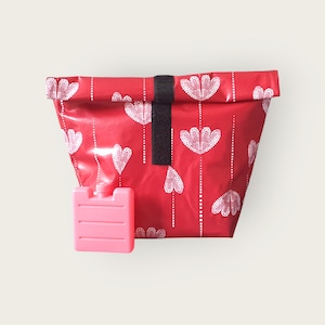 Könnte beinhalten: Rote isolierte Lunch-Tasche mit einem weißen Herzmuster und einem schwarzen Riemen. Ein rosa Kühlpad ist enthalten.