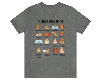 May include: A heather gray t-shirt with the text "THINGS I LOVE TO DO" above a grid of illustrated activities, including "Save the Earth," "Eat Watermelon," and "Go Swimming." The shirt features a crew neck and short sleeves.