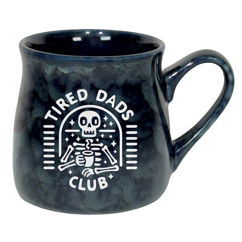 May include: A dark blue ceramic mug with a white graphic that reads "TIRED DADS CLUB". The graphic features a skeleton holding a coffee cup. The mug has a large handle and a speckled finish.
