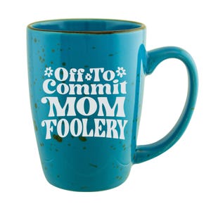 May include: A teal ceramic mug with a curved handle. The mug features the white text "Off To Commit MOM Foolery" in a playful font. The mug has a speckled design and a brown rim.