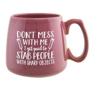 May include: A maroon ceramic mug with a large handle. The mug has the text "DON'T MESS WITH ME I get paid to STAB PEOPLE WITH SHARP OBJECTS" in white. Two syringe illustrations are on either side of the text.