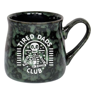 May include: A ceramic mug with a speckled green and black glaze. The mug features a white graphic of a skeleton holding a coffee cup, with the words "TIRED DADS CLUB" in a circular design.