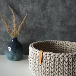 Una cesta decorativa tejida, un recipiente para guardar objetos pequeños, un elemento decorativo en un estante de una habitación o baño. Sand