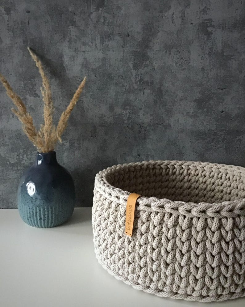 Una cesta decorativa tejida, un recipiente para guardar objetos pequeños, un elemento decorativo en un estante de una habitación o baño. Sand