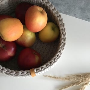 Una cesta decorativa tejida, un recipiente para guardar objetos pequeños, un elemento decorativo en un estante de una habitación o baño. imagen 5