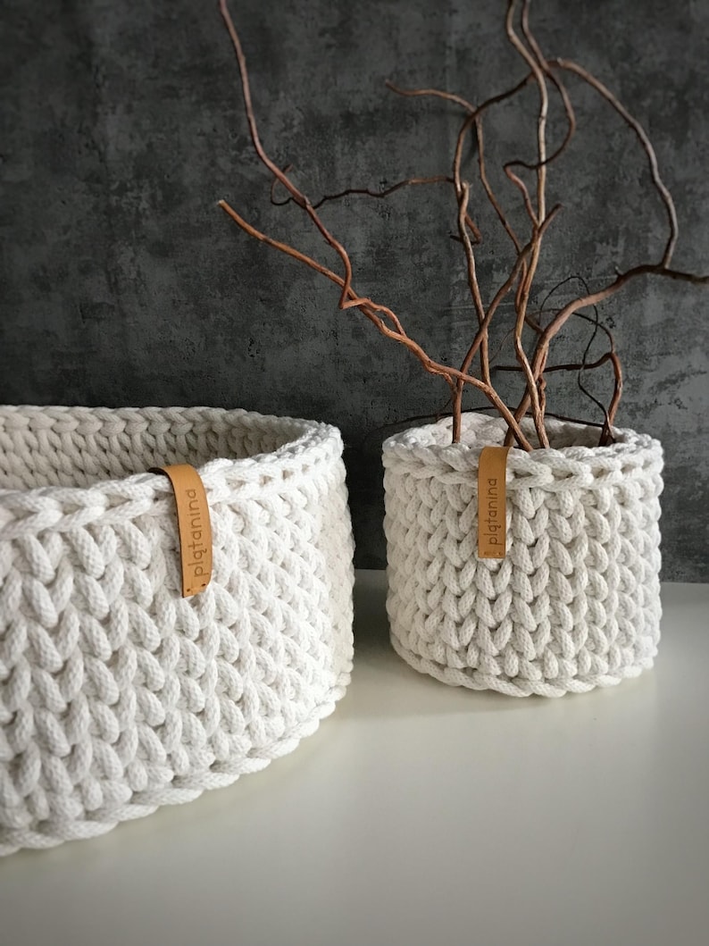 Una cesta decorativa tejida, un recipiente para guardar objetos pequeños, un elemento decorativo en un estante de una habitación o baño. Off white