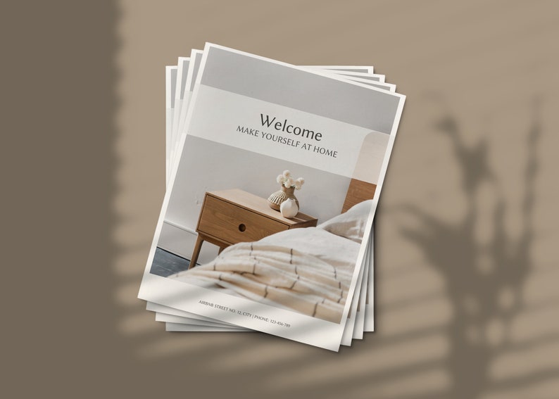 May include: A stack of brochures with a white background and the text "Welcome Make Yourself at Home". The brochure features a photo of a wooden nightstand with a drawer and a white ceramic vase with white flowers on top. A white and beige striped bedspread is visible in the background.