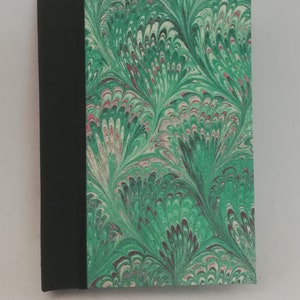 Puede incluir: Un pequeño cuaderno marmoleado verde y negro con una encuadernación negra. El patrón de marmoleado se asemeja a plumas.