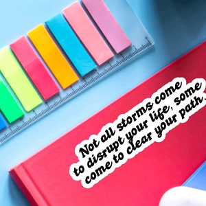 May include: A white sticker with black text on a red surface. The text reads "Not all storms come to disrupt your life, some come to clear your path."