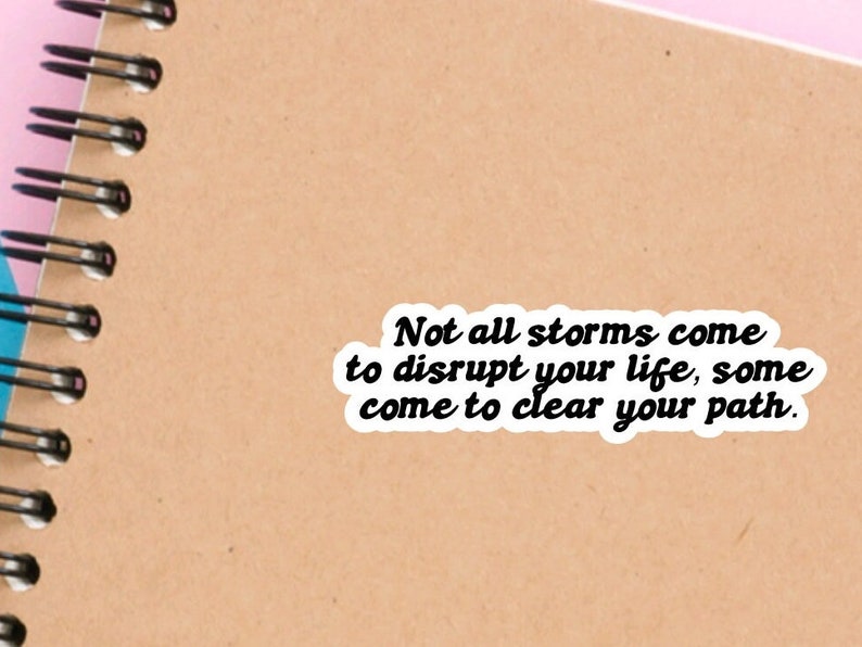 May include: A motivational quote sticker on a brown notebook. The quote reads: "Not all storms come to disrupt your life, some come to clear your path."