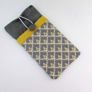 Puede incluir: Una funda para teléfono de tela gris y amarilla con un patrón geométrico. La funda tiene un botón amarillo y una cuerda blanca.