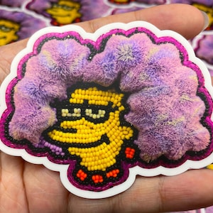 May include: A yellow cartoon character with purple hair, beaded eyes, and a beaded smile. The character is surrounded by a purple and white fuzzy texture. The image is a sticker.