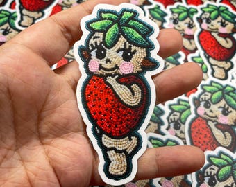 May include: A sticker featuring a cartoon strawberry character with a green leafy crown, red body, and white bead-like details. The character is holding a red strawberry in its hands.