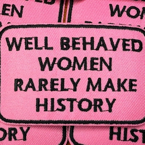 Peut inclure: Écusson rose brodé avec le texte "WELL BEHAVED WOMEN RARELY MAKE HISTORY" en noir. Le patch a une bordure noire et est probablement un article décoratif pour les vêtements ou les accessoires.