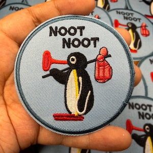 Könnte beinhalten: Eine weiße Keramiktasse mit schwarzem Henkel und dem Text "But First, Coffee" in schwarzer, handschriftlicher Schrift. Die Tasse steht auf einer weißen Oberfläche.